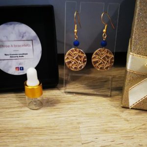 boucle d'oreille pièce motifs relief en acier inoxydale doré et une perle de lave bleu foncé