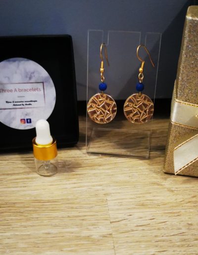 boucle d'oreille pièce motifs relief en acier inoxydale doré et une perle de lave bleu foncé