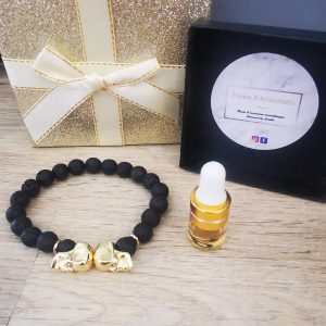 bracelet pierre de lave et 2 tetes de mort doré a strass