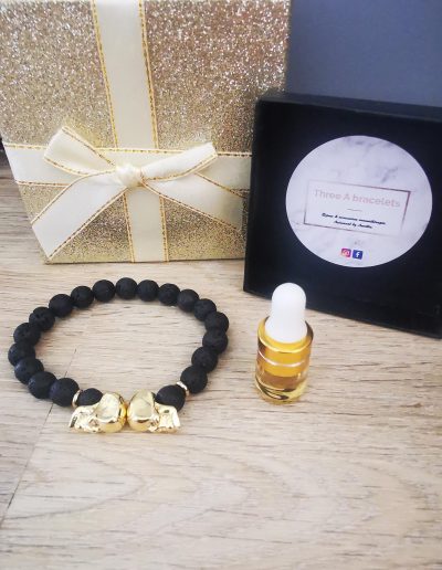 bracelet pierre de lave et 2 tetes de mort doré a strass